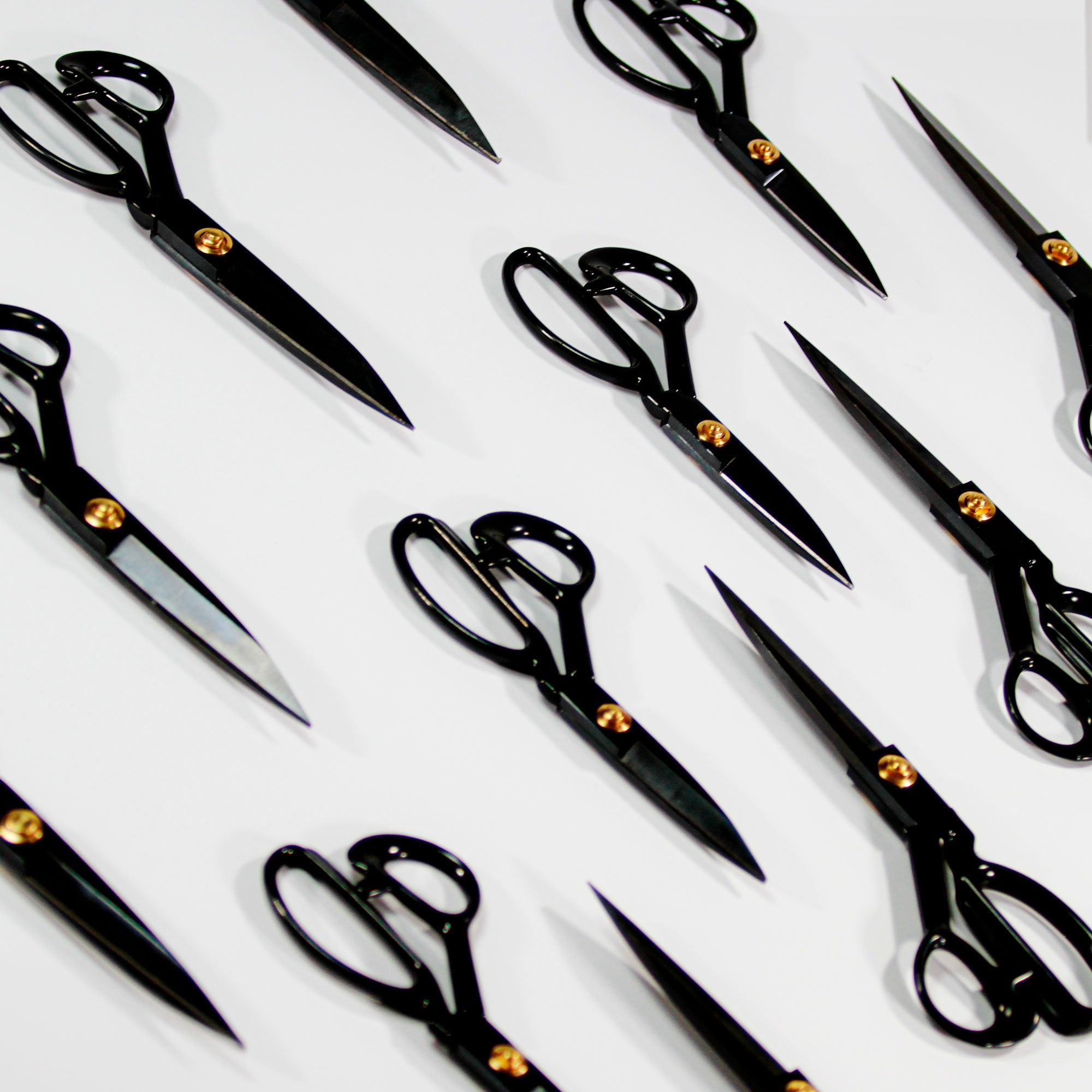 Multiple black textile scissors arranged diagonally on a white background – ideal for precise fabric, yarn, and tufting cuts.