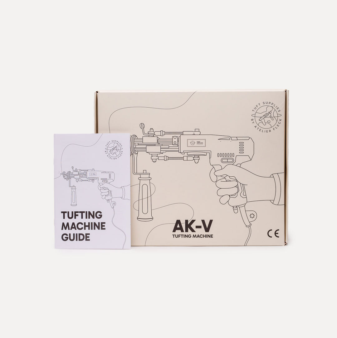 A product box and a printed instruction guide for a tufting machine, shown on a light gray background. The box is beige with black line drawings of the machine and the text 'AK-V TUFTING MACHINE'.
