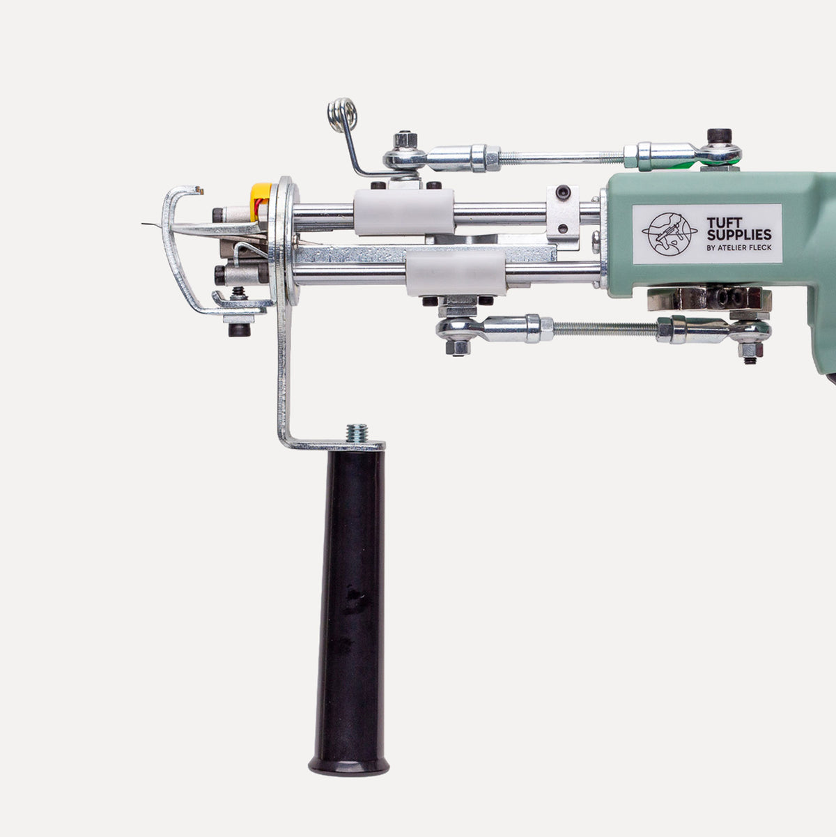 A close-up of a Tuft Supplies machine component with a black handle, silver metal rods, white plastic rollers, and a mint green housing on a light gray background.